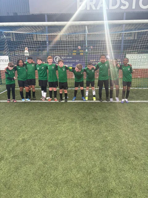 Squad celebrating in front of the goal