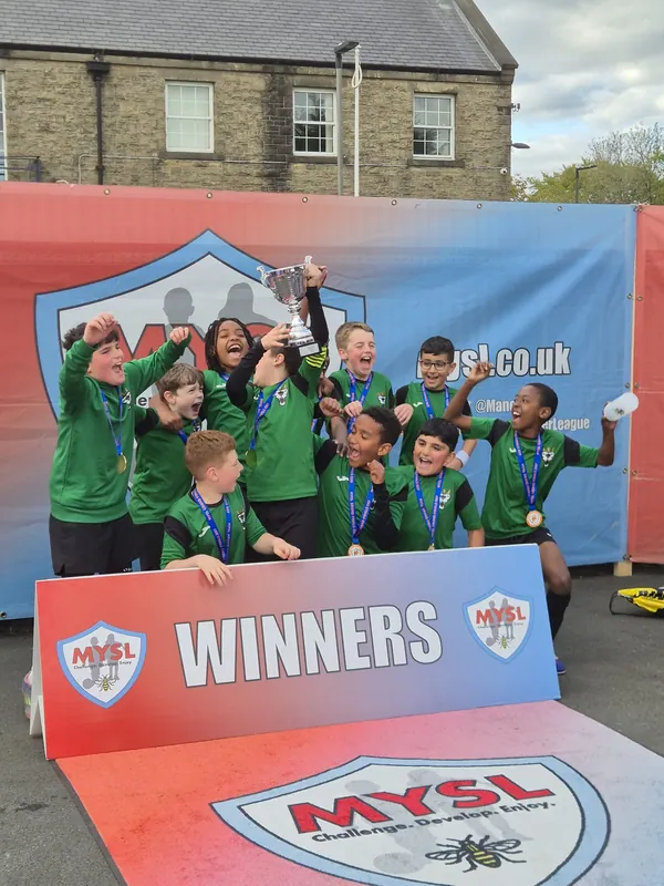 FC Babylon boys lifting the cup behind an MYSL Winners banner