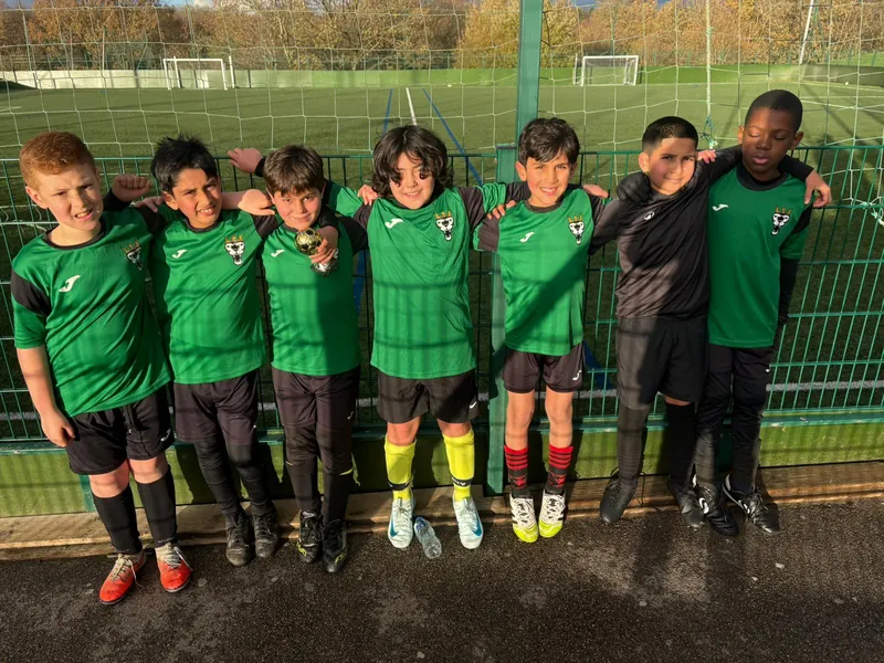 FC Babylon boys arm in arm on the pitch in their green kits